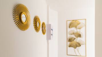 A wall with three golden sunburst mirrors and a framed artwork of golden leaves.