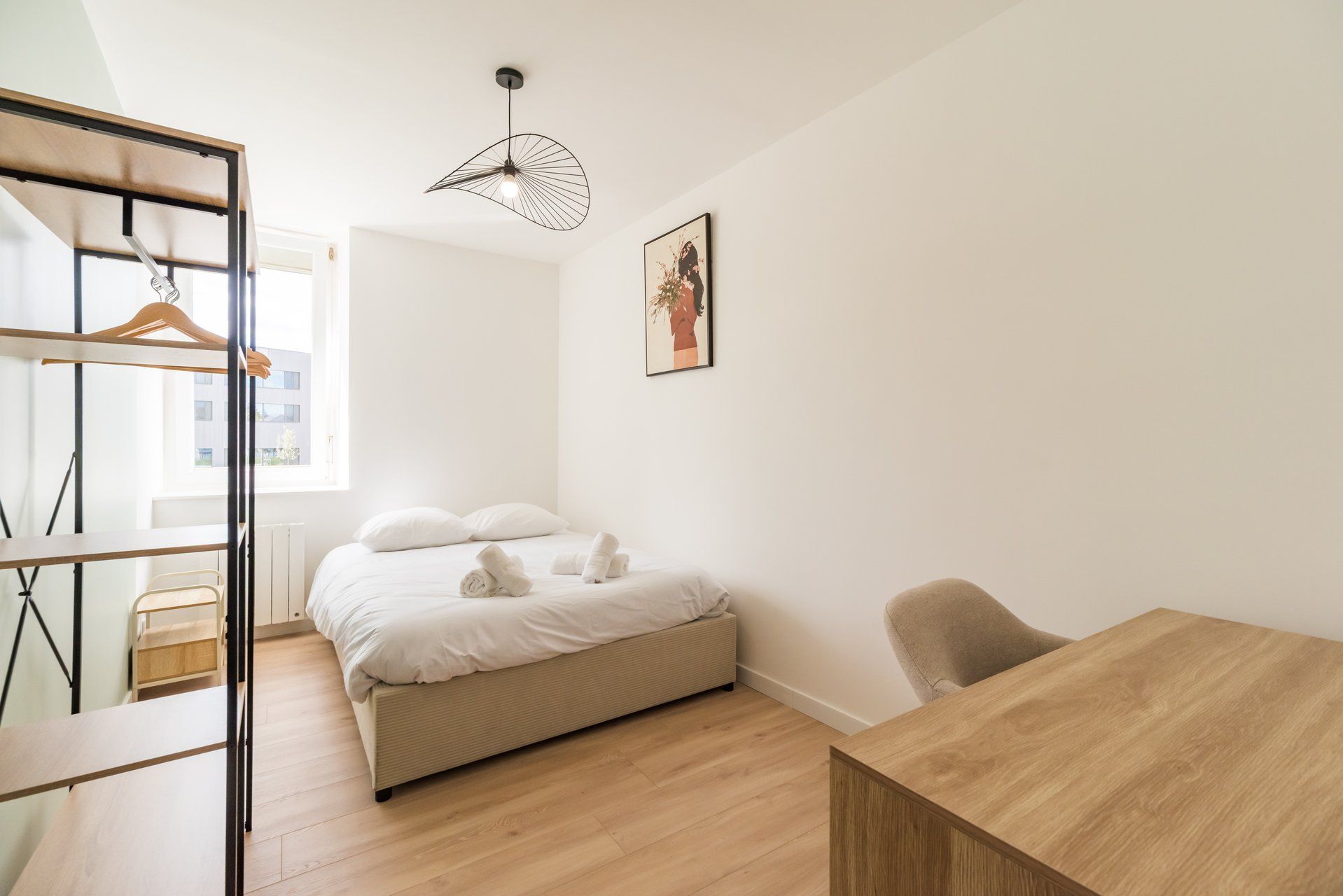 Une chambre à coucher au style minimaliste, avec un lit, un bureau et un luminaire suspendu.