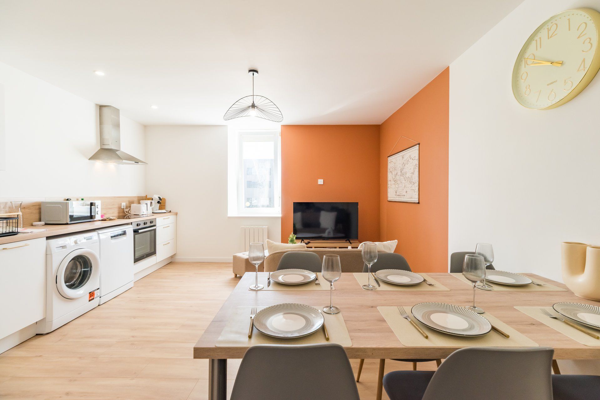 Une cuisine moderne avec un coin repas, un lave-linge et un téléviseur à écran plat.