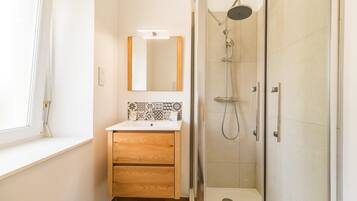 Une salle de bain avec une douche, un miroir et un lavabo.