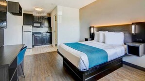 Ein Hotelzimmer mit Bett, Nachttischen, einem Schreibtisch und einer Küchenzeile.