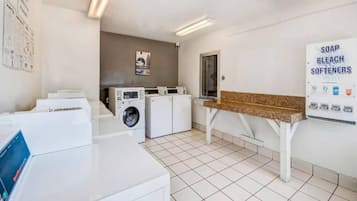A laundry room with a washing machine, dryer, and a soap and bleach dispenser.