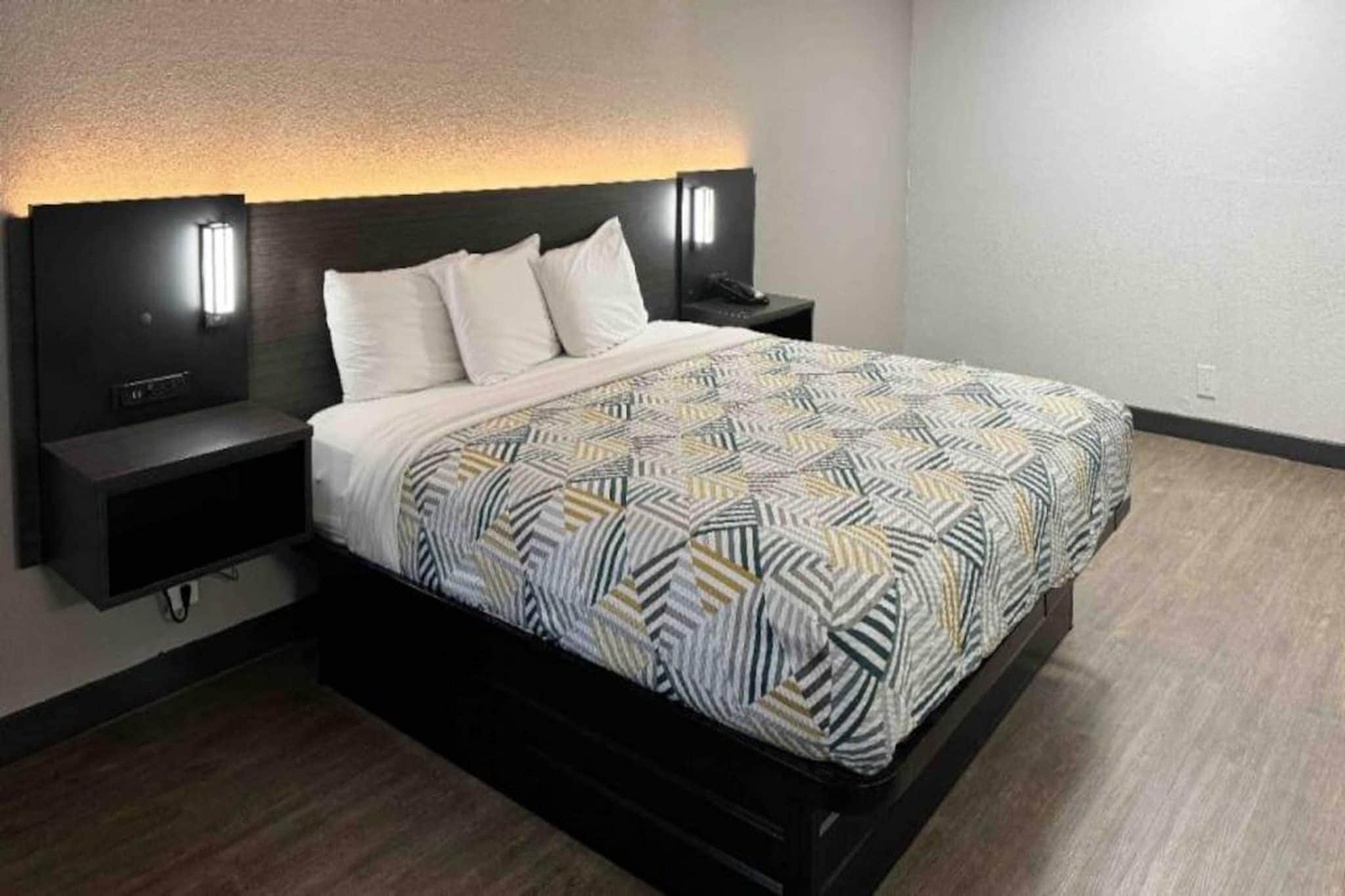 A modern bedroom with a bed, nightstands, and wall-mounted lights.