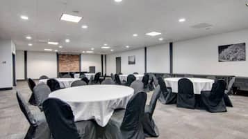 A conference room with round tables, chairs, and a projector screen.