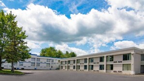 A multi-story motel with a parking lot and a clear sky.