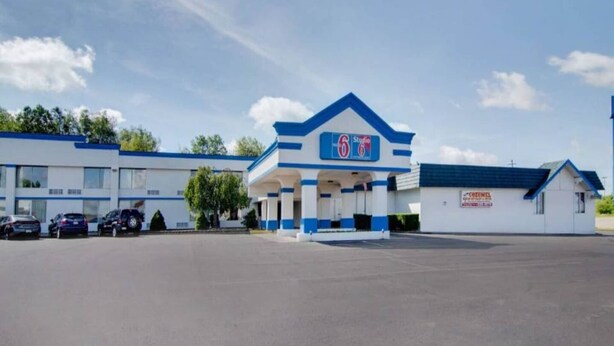 A 6-star hotel with a blue and white exterior, a parking lot, and a small adjacent building.