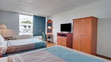 Una habitación de hotel con dos camas, un escritorio con computadora, televisor y armario.