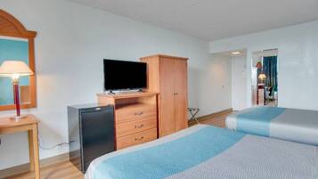 Una habitación de hotel con una cama, un escritorio con lámpara, un televisor y un armario.