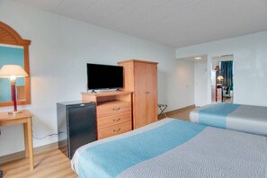 Une chambre d’hôtel comprenant un lit, un bureau avec une lampe, une télévision et une armoire.