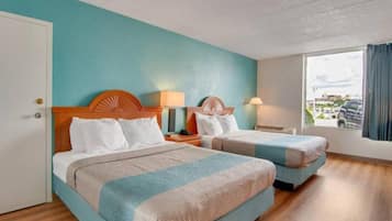 Une chambre d’hôtel avec deux lits, une fenêtre donnant sur un paysage agréable et une porte.