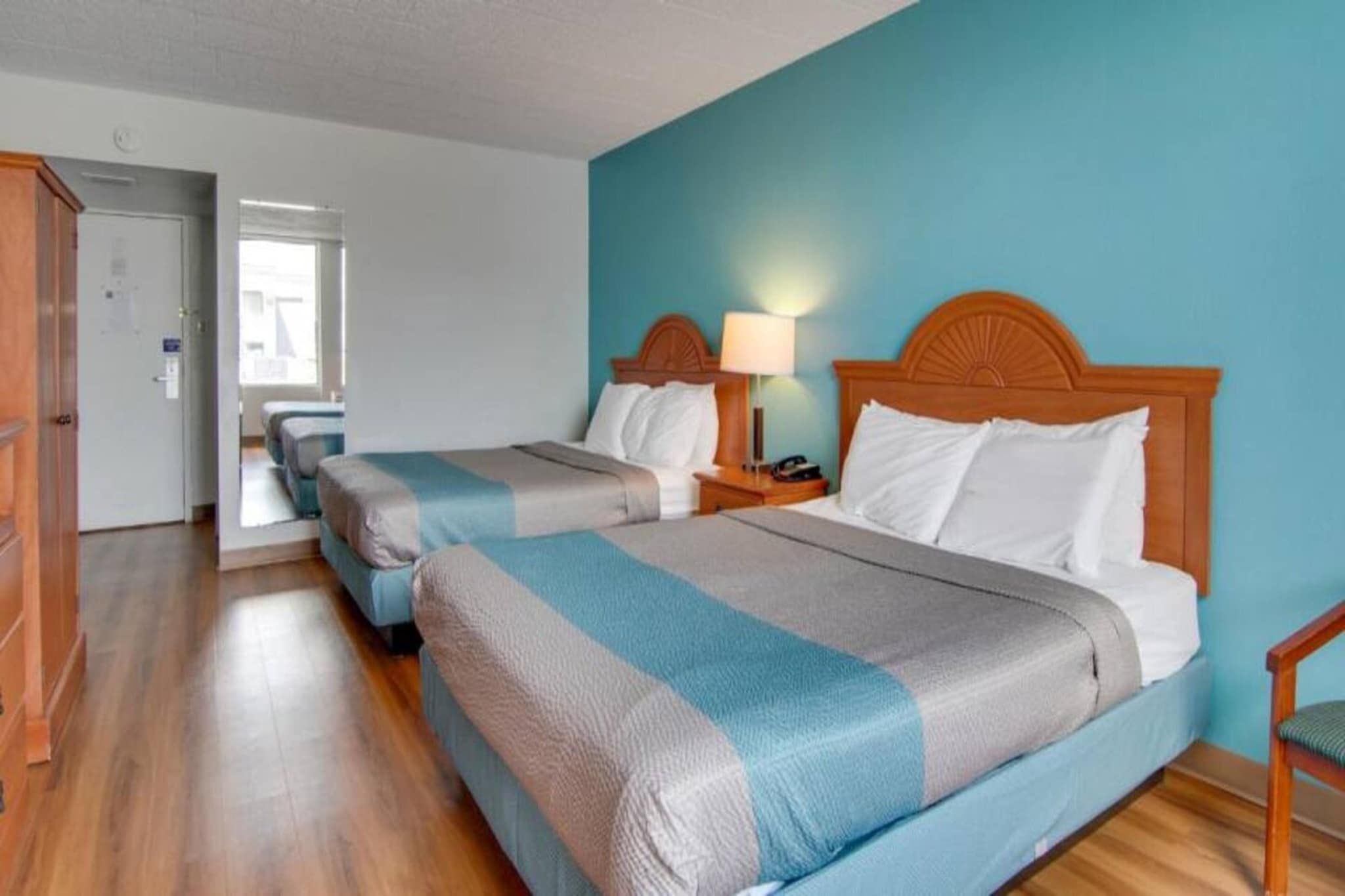 Ein Hotelzimmer mit zwei Betten, Holz Kopfteilen, Nachttischlampen und einem Holzboden.