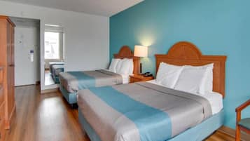 Ein Hotelzimmer mit zwei Betten, Holz Kopfteilen, Nachttischlampen und einem Holzboden.