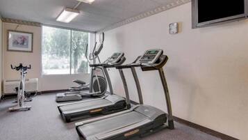 Een fitnessruimte met loopbanden, een hometrainer en een roeimachine.