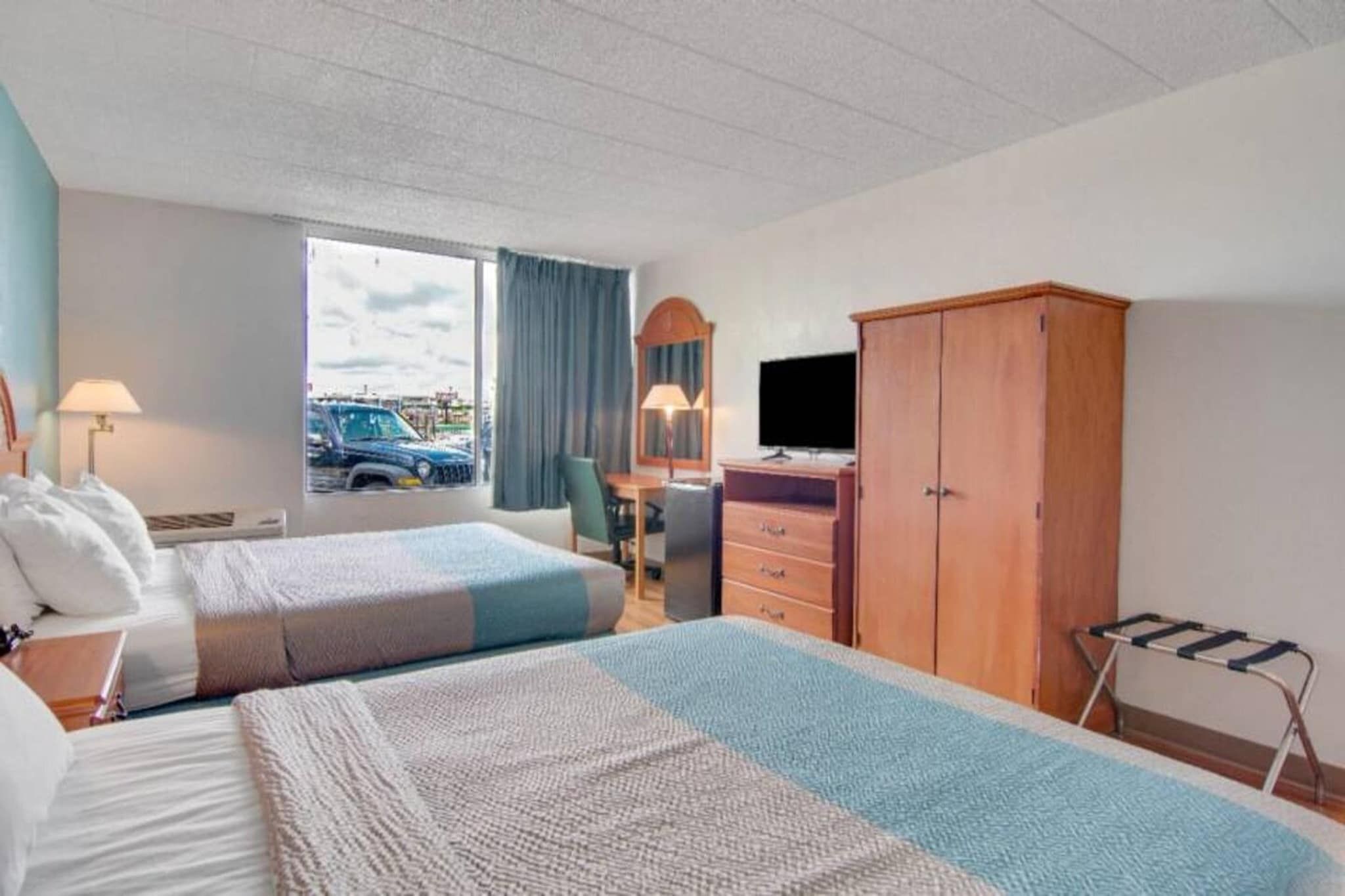A hotel room with two beds, a desk, a TV, and a wardrobe.