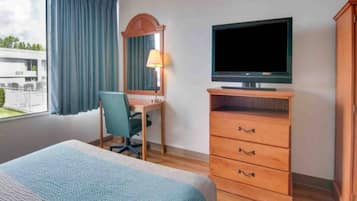 Una habitación de hotel con una cama, un escritorio con una silla, un televisor y un armario.