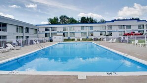Una piscina amb superfície d'aigua blava cristal·lina, envoltada d'una tanca blanca.