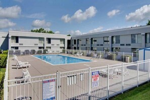 A hotel with a swimming pool surrounded by lounge chairs and a fenced area. - 1 King Bed|Non-Smoking, Micfridge (Clarion)
