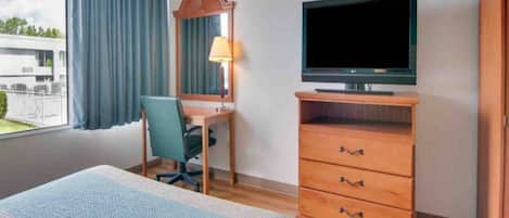 A hotel room with a bed, a desk with a chair, a television, and a wardrobe.