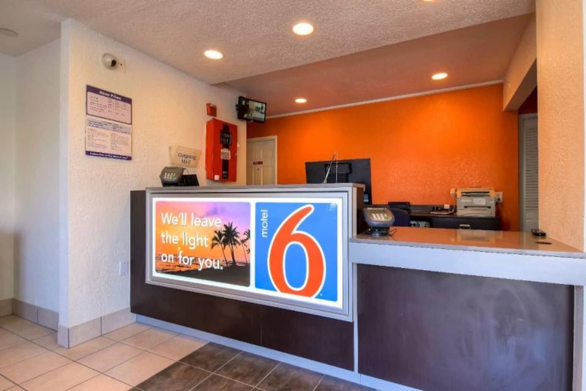 A hotel reception desk with a digital display, a telephone, and a cash register.