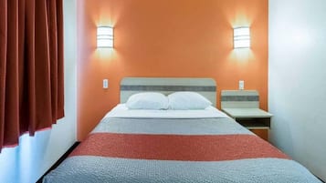 A hotel room with a bed, two bedside tables, and two wall-mounted lamps.