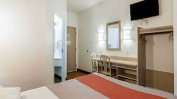 A hotel room with a bed, a desk with chairs, a television, and a wardrobe.
