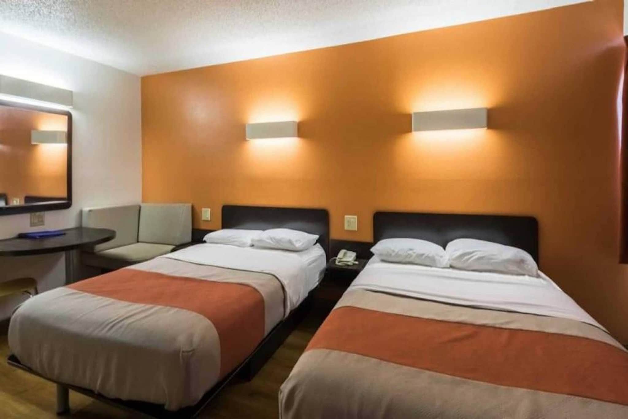 Une chambre d’hôtel avec deux lits, un bureau et une chaise.