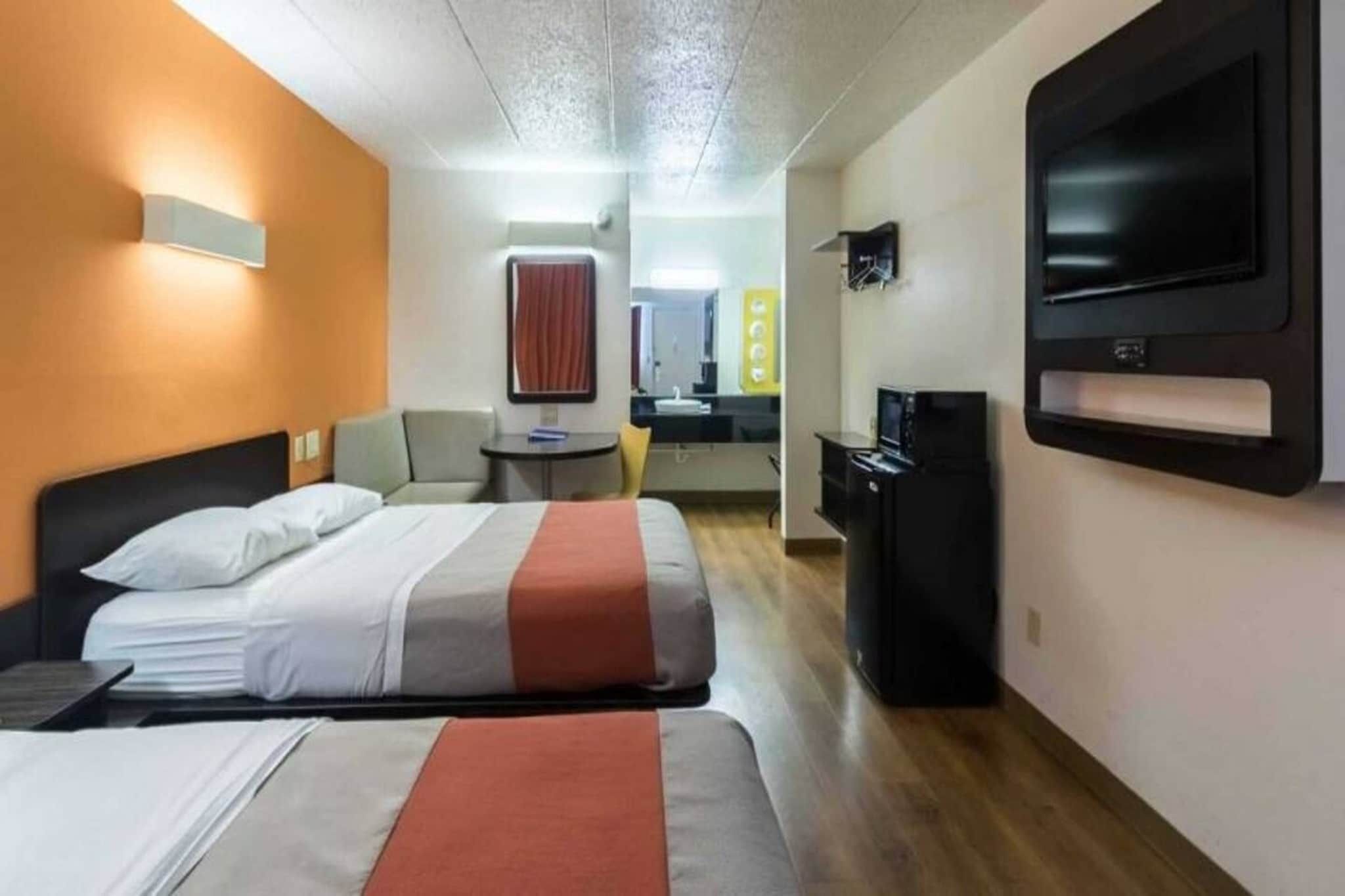 Ett hotellrum med två sängar, ett skrivbord, en tv och ett litet pentry.