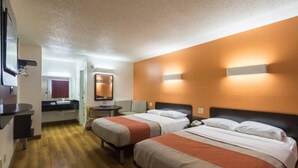 Habitación de hotel con dos camas, un escritorio, un espejo y un baño.