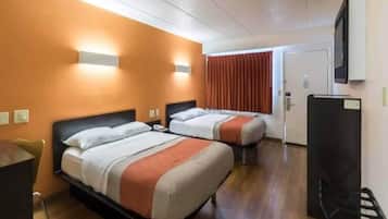 A hotel room with two beds, a desk, a chair, and a television.