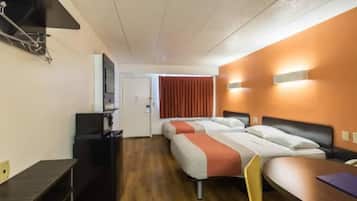 A hotel room with a bed, a desk, a chair, a TV, and a window with curtains.
