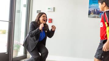 A person in a black suit and blue shirt running towards a door with a sign above it.