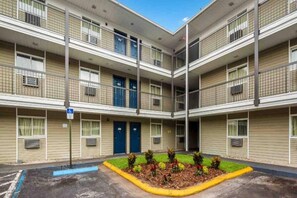 Um motel com vários andares e um pátio central, quartos individuais em cada andar e um sinal azul de acessibilidade para pessoas com deficiência.