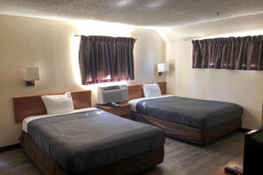 A hotel room with two beds, a bedside table, an air conditioning unit, and curtains. - 2 Full Beds | Smoking, Kitchen (Jacksonville)