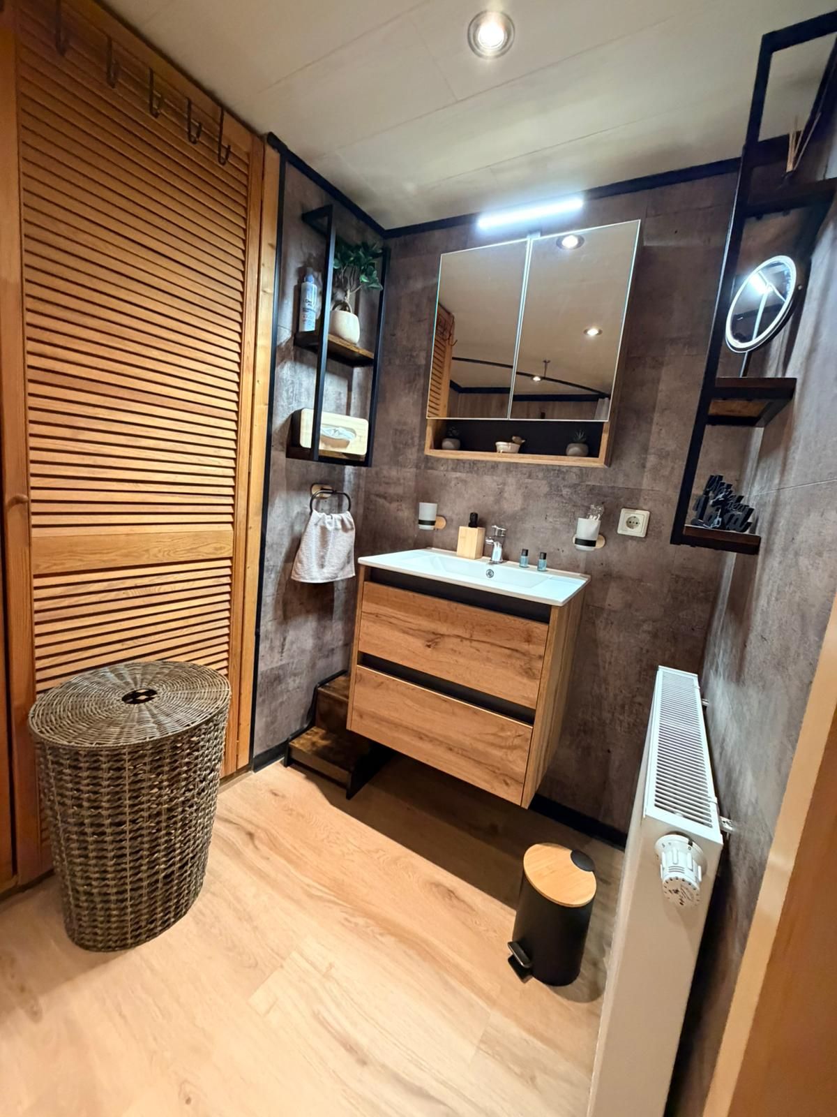 A modern bathroom with a wooden vanity, a mirror, and a built-in heater.