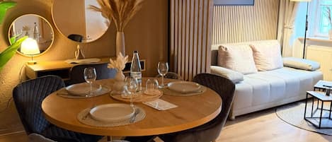 A dining area with a round table set for four, surrounded by chairs.
