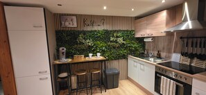 A modern kitchen with a built-in herb garden, a coffee machine, and a stainless steel range hood. - Apartment 2 at Blankenburger Tor: downtown location, modern and cozy. (Saalfeld/Saale)