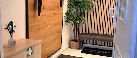 Ein modernes Interieur mit Holztür, Spiegel, Zimmerpflanze, Bank und einer kleinen Tierfigur.