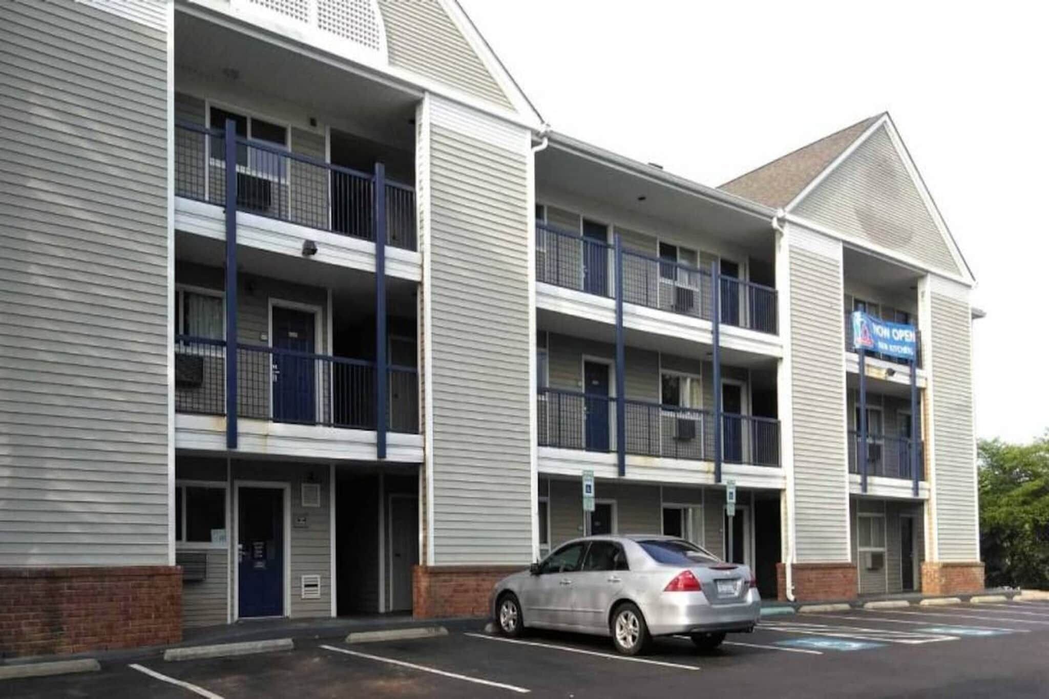 A multi-story hotel with a parking lot and a car parked in front.