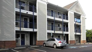 Et hotel med flere etager, en parkeringsplads og en bil foran.