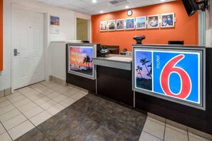 A reception area with a counter, a clock, and a wall with framed pictures.