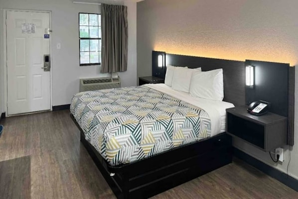 Een hotelkamer met een bed, nachtkastjes, een bureau, een stoel, een raam en een deur.