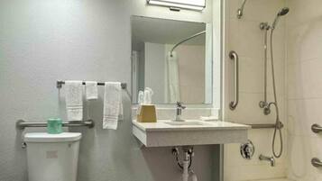 Een badkamer met toilet, wastafel, spiegel en douche.