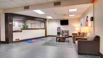 Un hall de hotel con mostrador de recepción, zona de estar y un televisor de pantalla plana montado en la pared.
