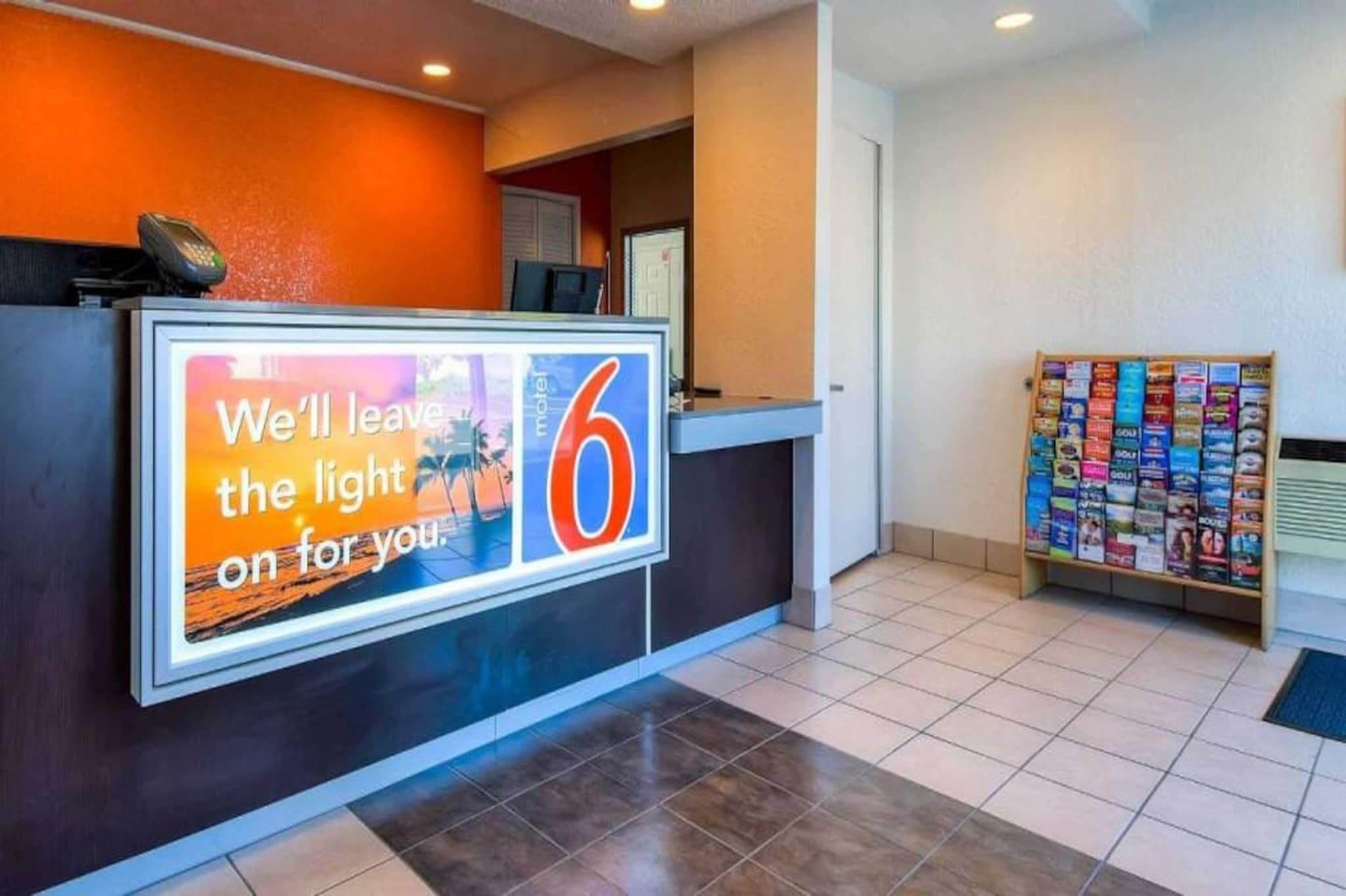 Zona de recepció d'un hotel amb un cartell gran que diu 'Deixarem la llum encèsa per tu'.