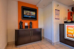 A reception area with a flat-screen TV mounted on the wall, a dark-colored reception desk, and a sign with partially visible text. - 1 Queen Bed|Deluxe|Rowland Heights (Rowland Heights)