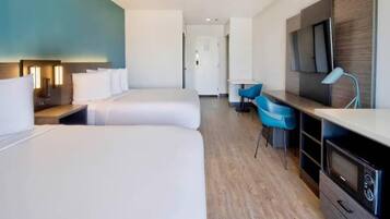 A hotel room with two beds, a desk, a chair, a TV, and a microwave.