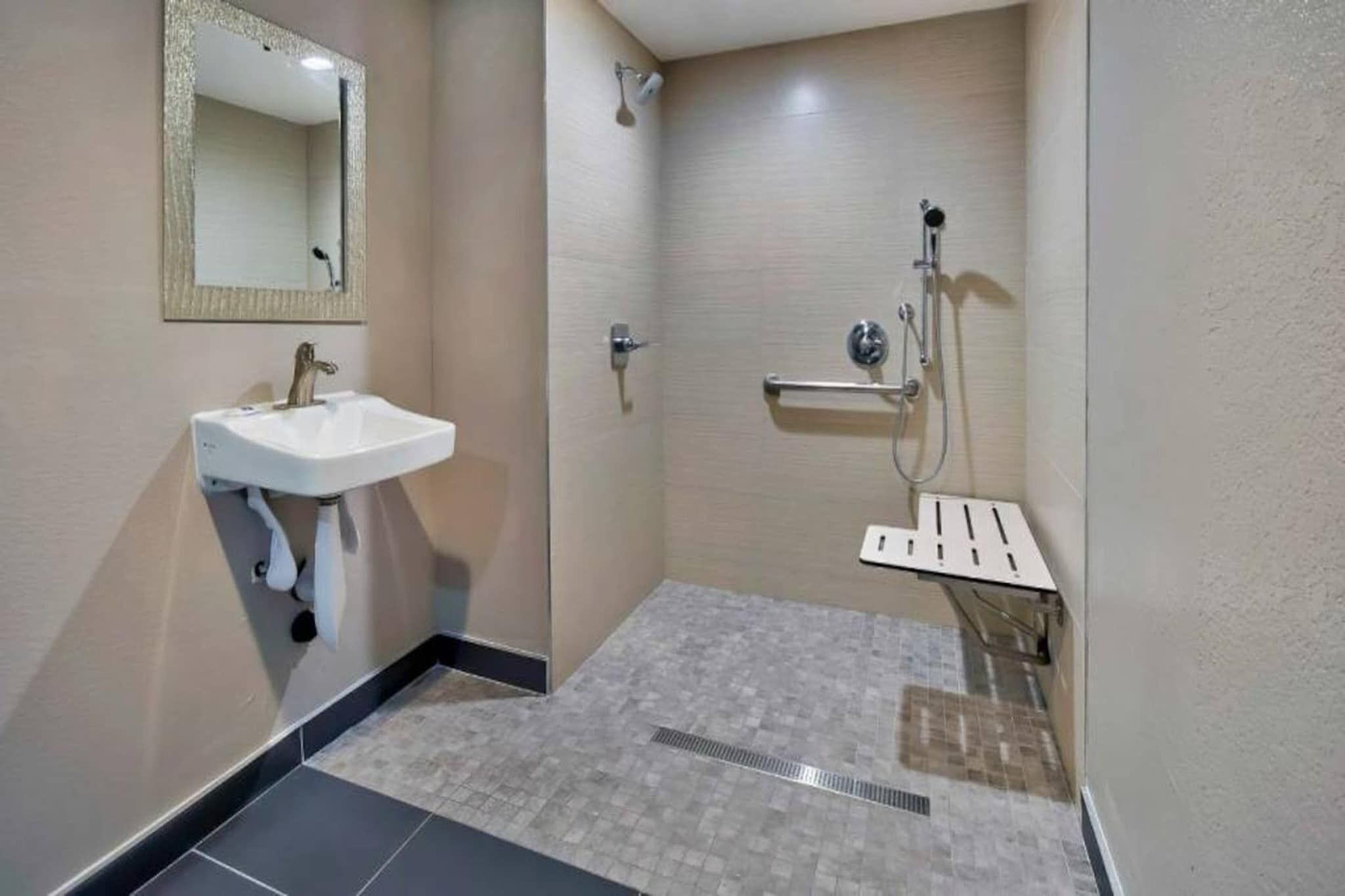 Ein Badezimmer mit Waschbecken, Spiegel, Dusche und Fliesenboden.