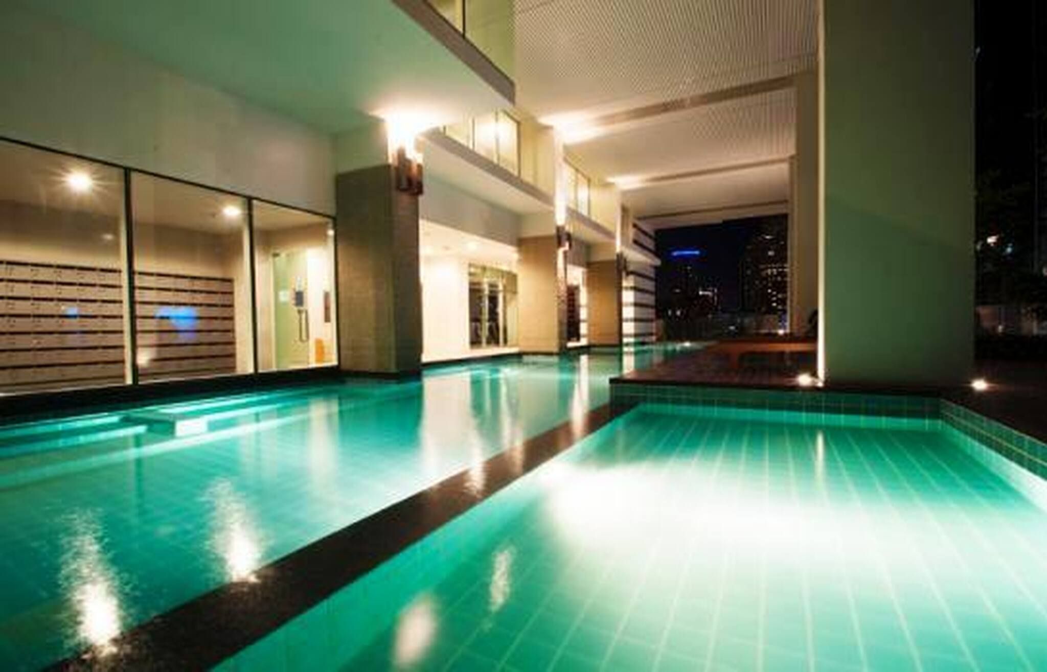 Ein Schwimmbad mit Blick auf die Stadt bei Nacht.