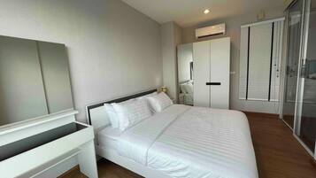 A modern bedroom with a bed, a desk, a wardrobe, and a sliding glass door.