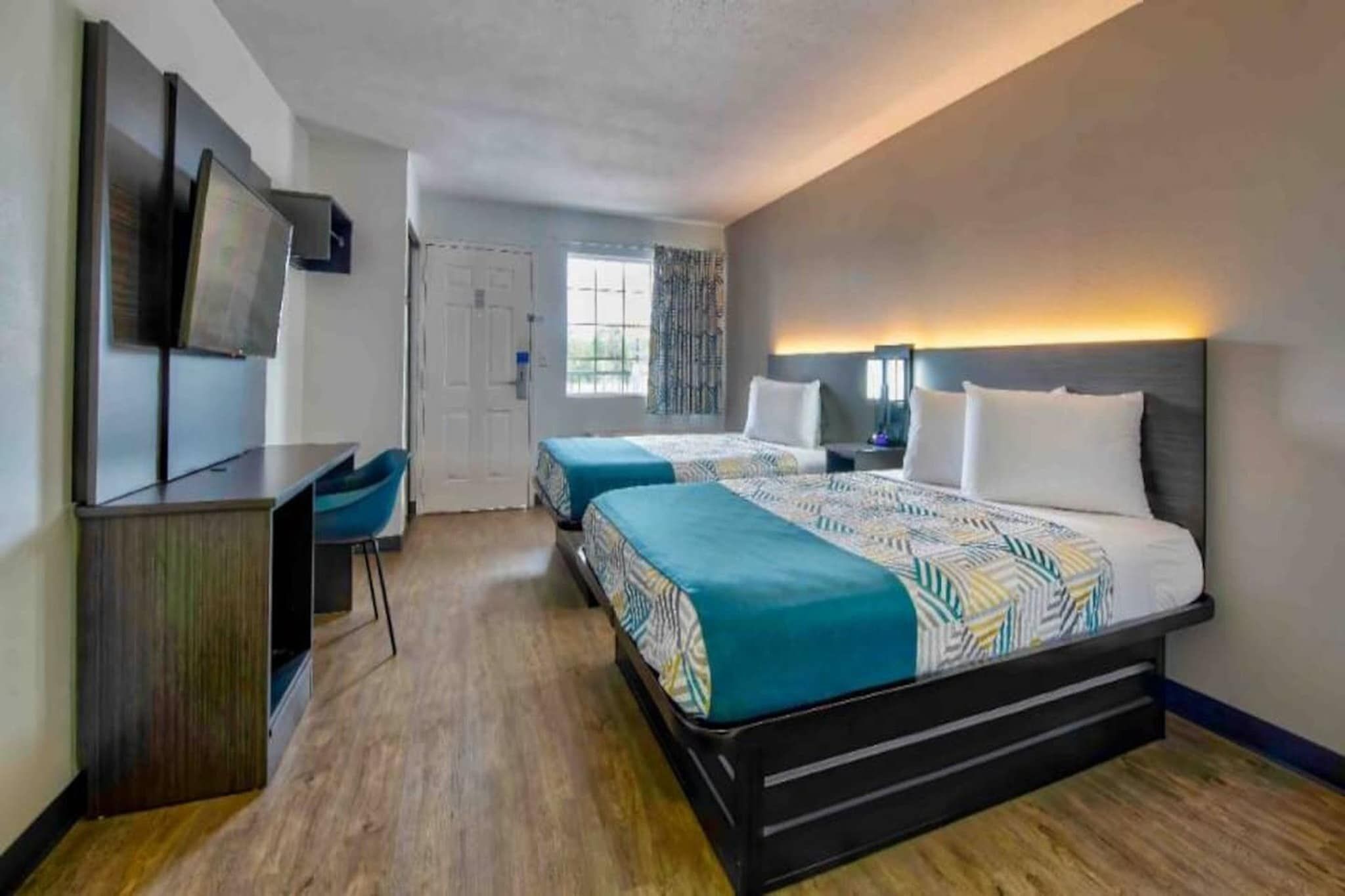 A hotel room with a large bed, a desk, and a TV.